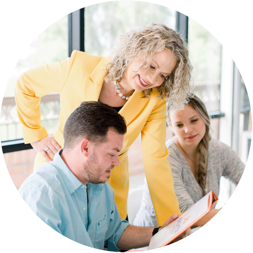 Woman facilitating a group discussion with two participants in a bright room.