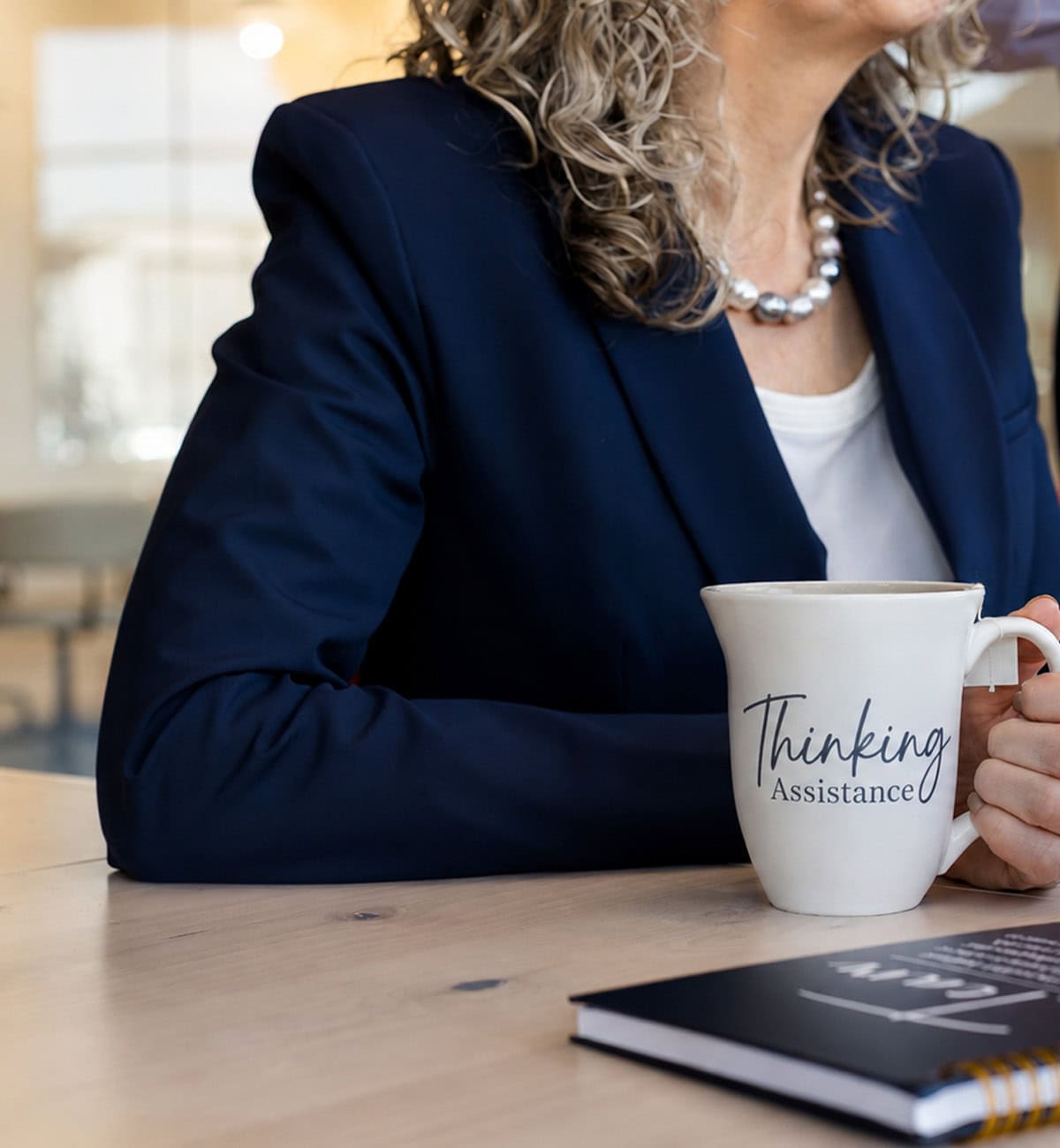Woman holding a coffee mug with 'Thinking Assistance' written on it.